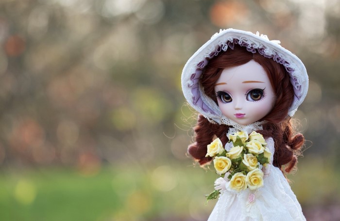 Doll with brown hair holding a bouquet of yellow roses