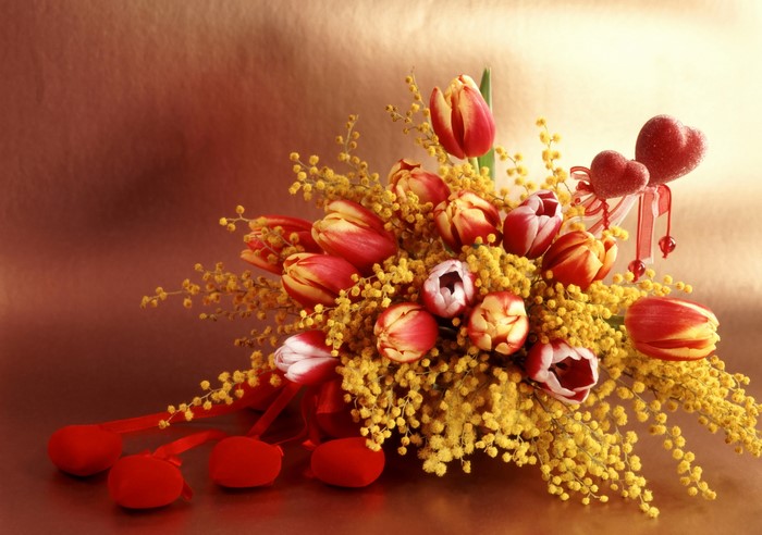 Bouquet of red and yellow tulips with mimosa and hearts