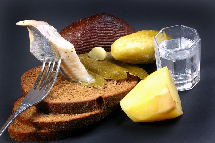 Still-life of herring, bread, pickles, potato, and vodka