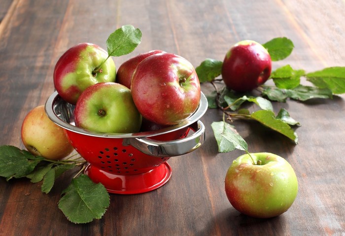 Apples in a red colander with leaves