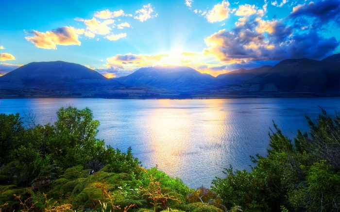 Sunrise over a calm lake with mountains and clouds