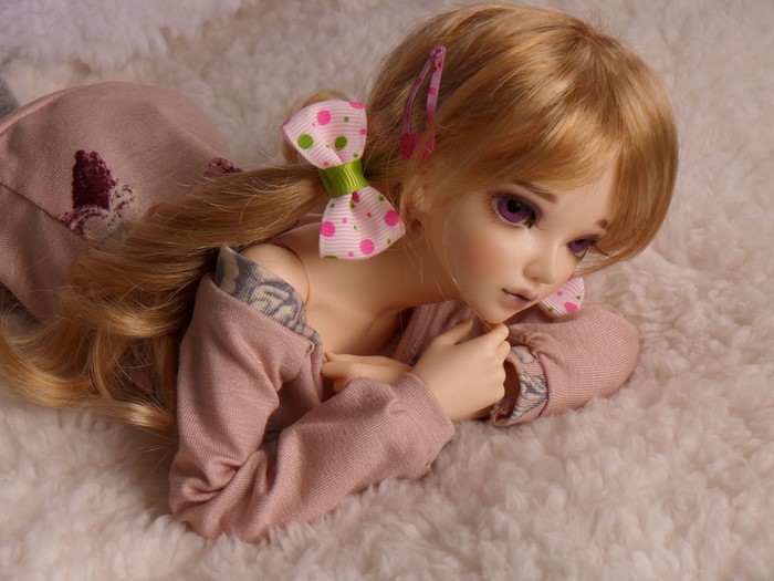 Doll with blonde hair and purple eyes wearing a pink dress