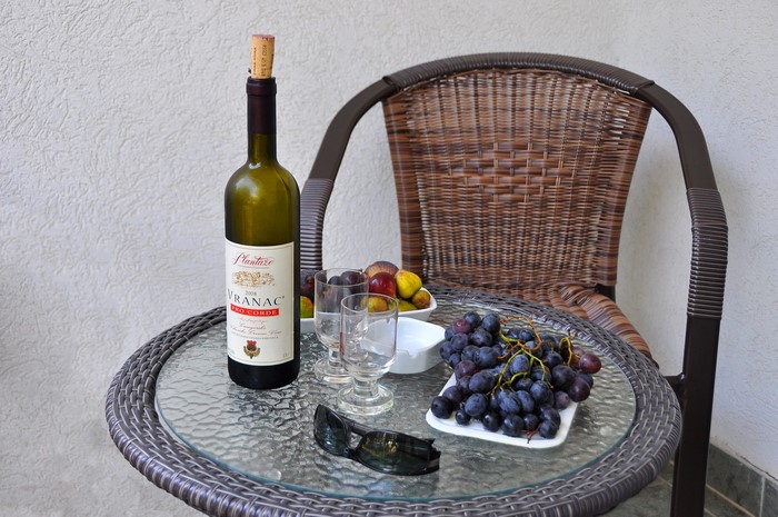 VRANAC wine bottle, grapes, fruit, and glasses on a table