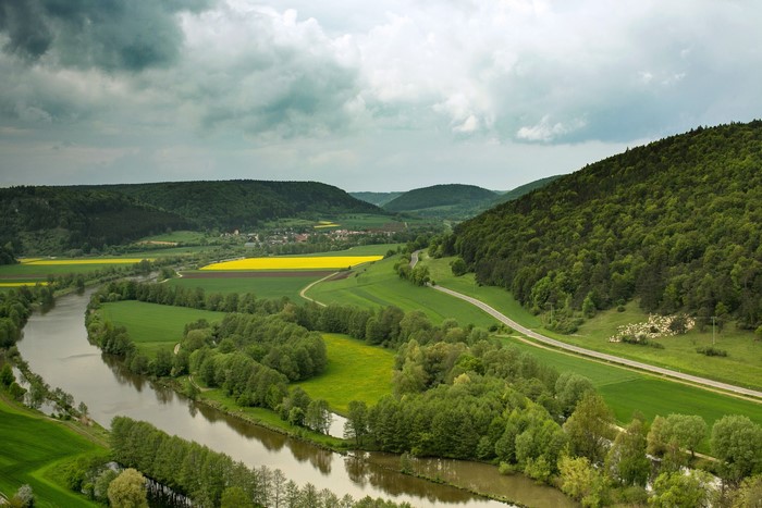 River valley with rapeseed fields and forests in Bavaria, Germany