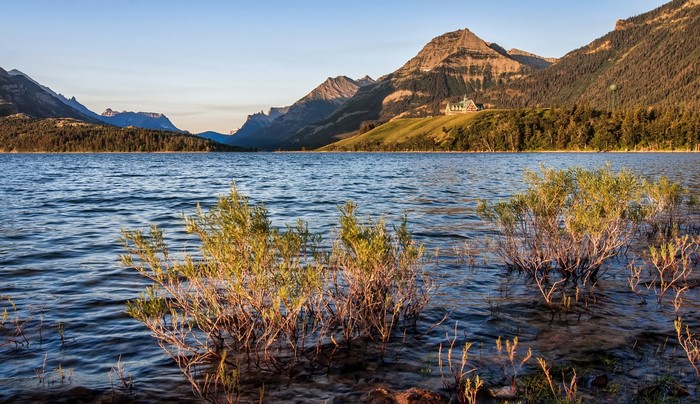 Prince of Wales Hotel on a hill overlooking a lake with mountains