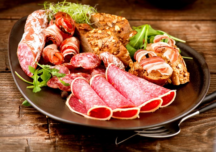 Charcuterie board with salami, bread, and greens