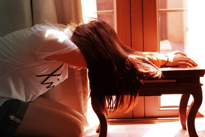 Brown haired person resting head on table
