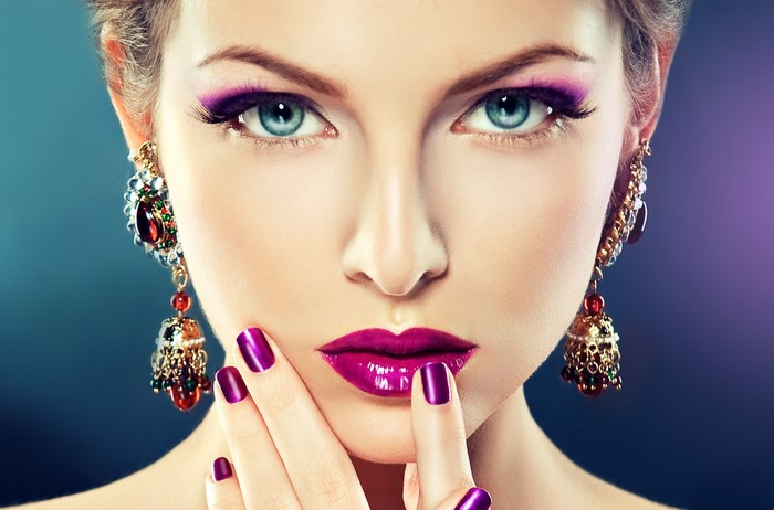 Woman with purple makeup and ornate earrings