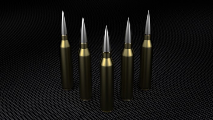 Five rifle cartridges on a black textured surface
