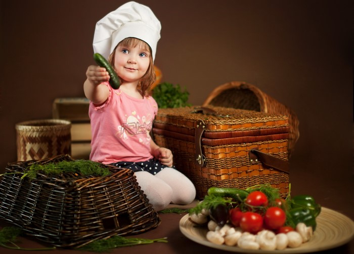 Little girl in chef hat with vegetables