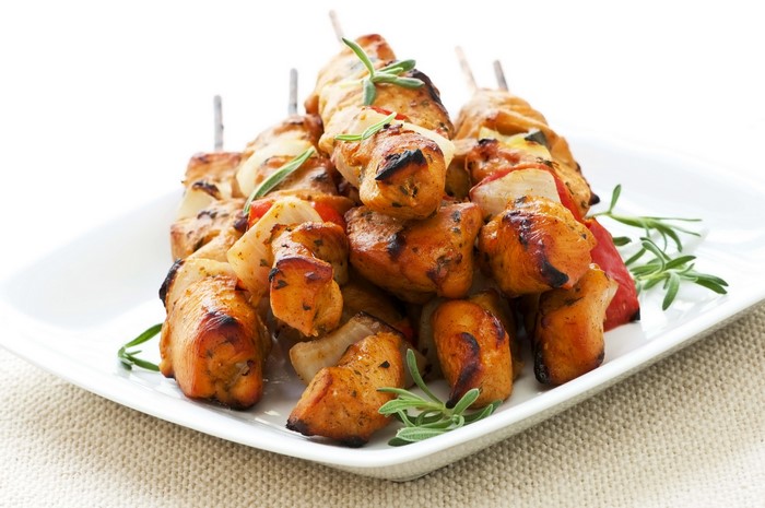 Chicken skewers with vegetables on a white plate