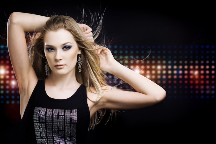Woman with dark blonde hair wearing a singlet and earrings