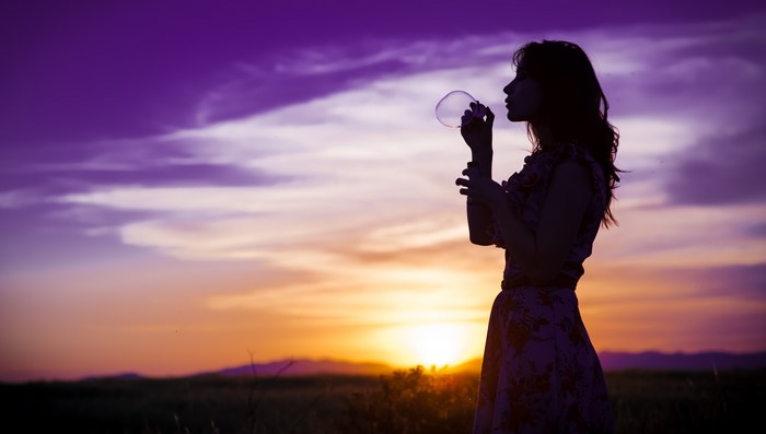 Silhouette of a woman blowing bubbles at sunset