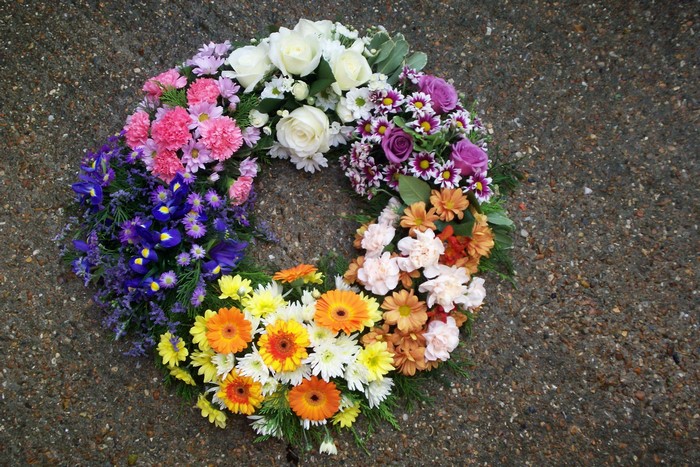 A circular wreath of colorful flowers on a concrete surface