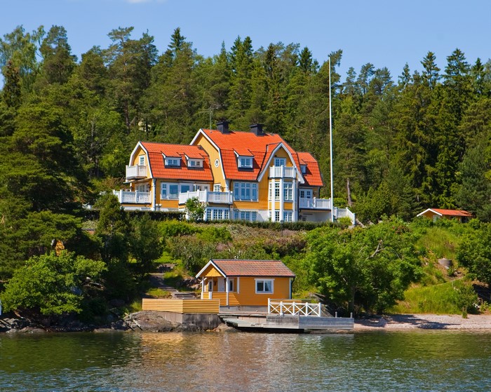 Yellow houses on a wooded hillside by the water in Resaro, Sweden