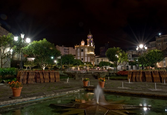 Plaza at night with fountain and church in Galicia, Spain