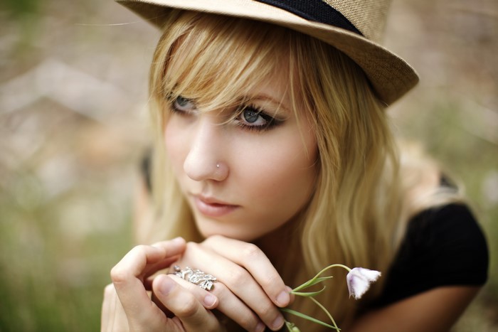 Blonde girl wearing a hat holding a flower