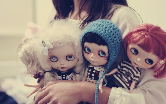 Three Blythe dolls held by a person