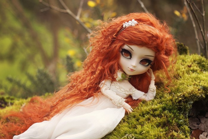 Doll with long red hair lying on moss