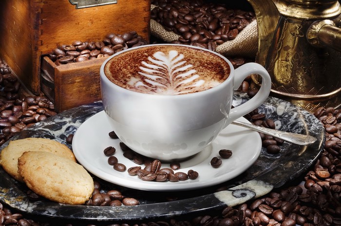Cappuccino with latte art, cookies, and coffee beans