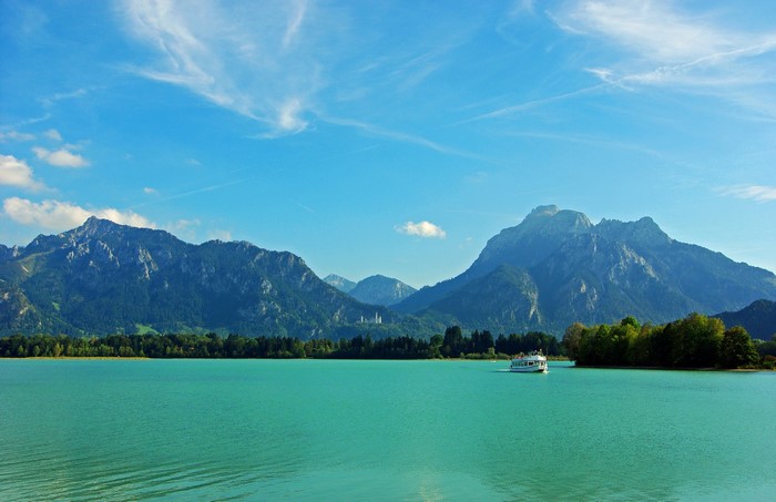 Turquoise lake with mountains and a boat in Bavaria, Germany