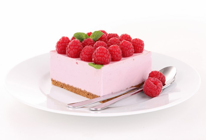 Raspberry cheesecake on a white plate with spoons