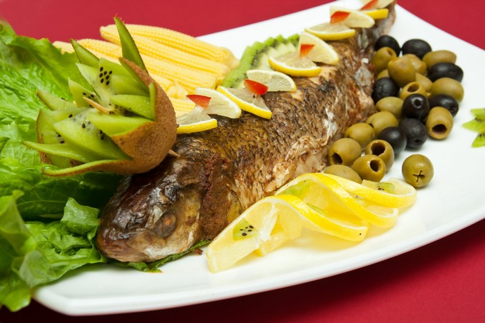 Whole roasted fish with kiwi, lemon, olives, and corn