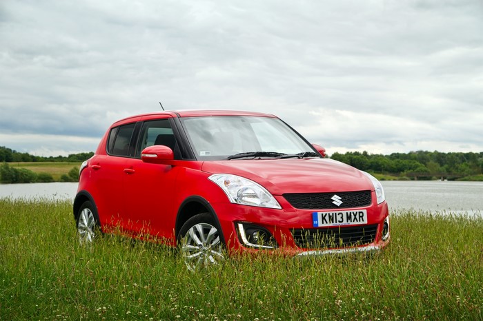 Red 2013 Suzuki Swift 4x4 SZ4 parked in grass by a lake