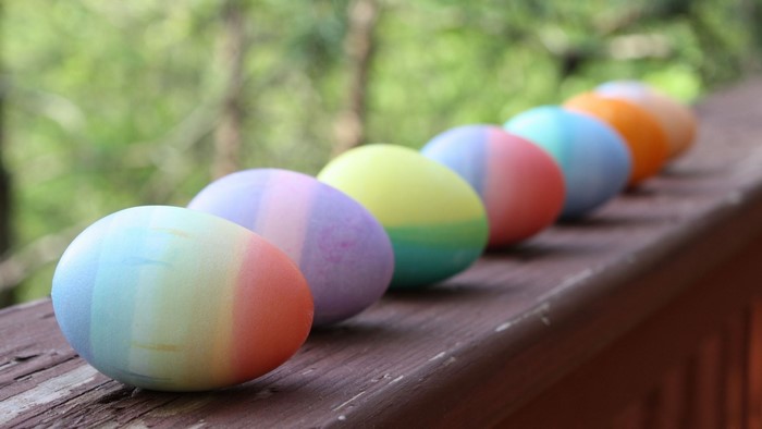 Rainbow Easter Eggs on a Wooden Railing