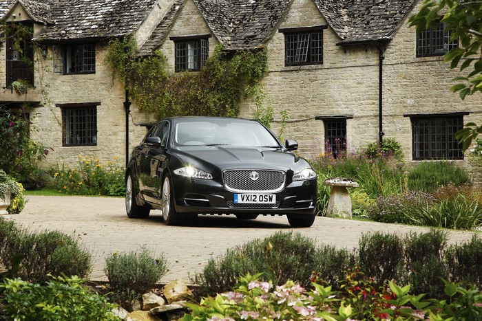 Black Jaguar XJ parked in front of a stone house