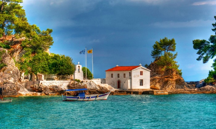 White church and bell tower on a rocky coast in Greece