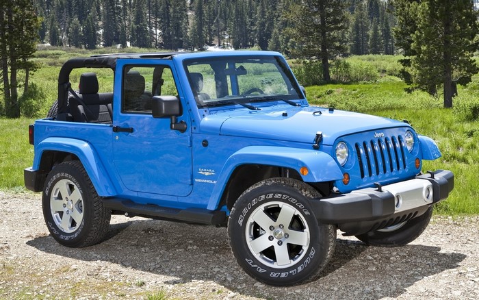 Blue Jeep Wrangler Sahara parked on a dirt road