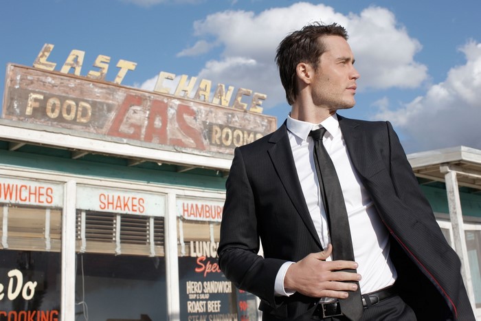 Man in suit in front of a vintage gas station