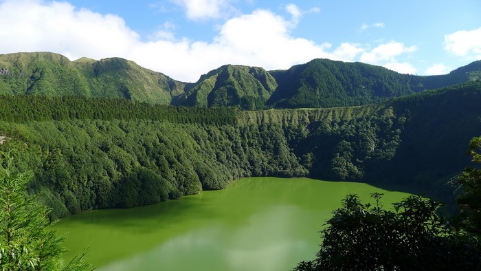 Green lake surrounded by forested mountains in the Azores, Portugal