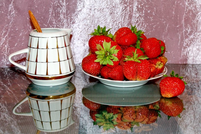 Strawberries in a bowl with a creamer and spoon