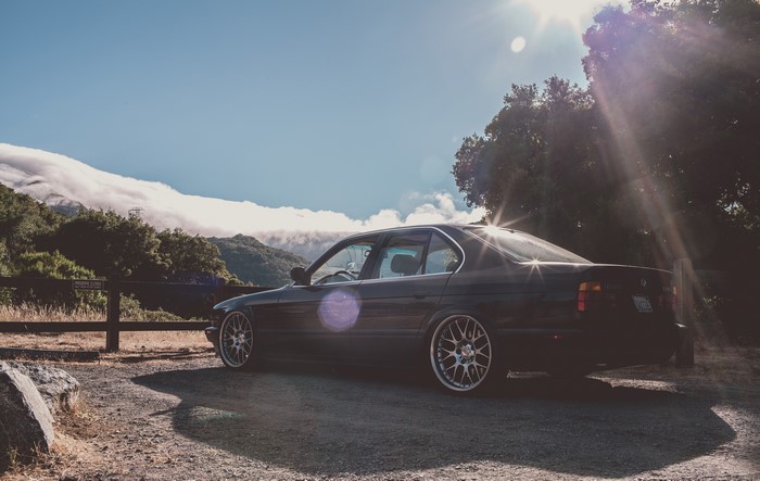 BMW E34 parked on a dirt road with mountains in the background