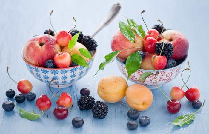Bowls of fresh fruit with peaches, cherries, blueberries, and blackberries
