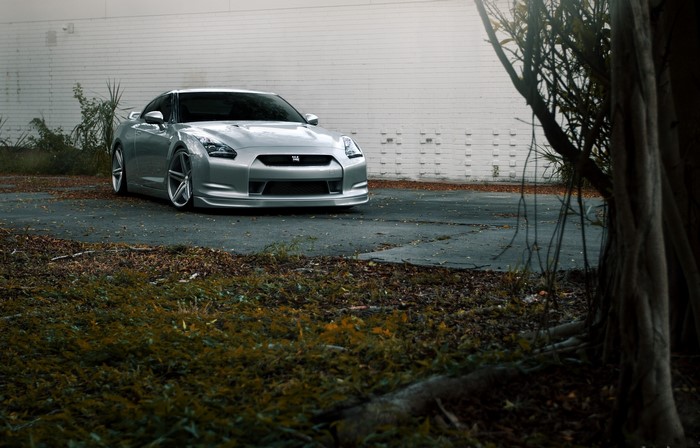 Silver Nissan GT-R R35 parked near a brick wall