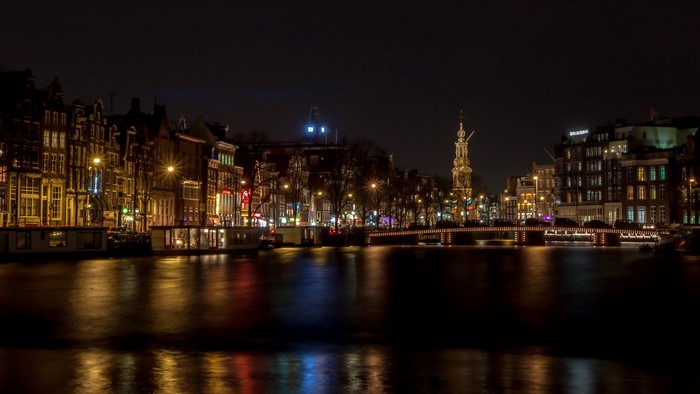 Amsterdam canal at night with illuminated buildings and bridge