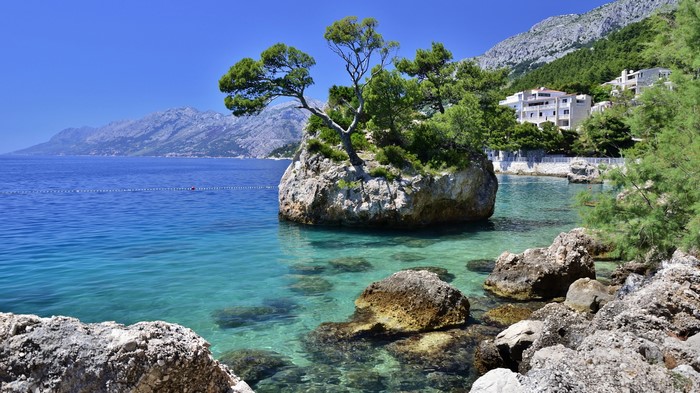 Rocky coast with clear turquoise water and mountains in Croatia