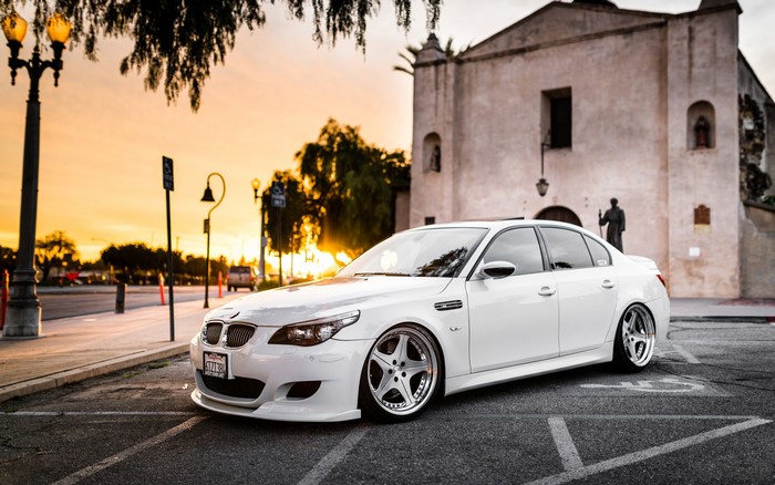 White BMW M5 parked on street at sunset