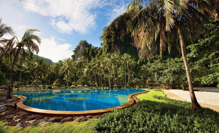 Resort pool with palm trees and cliffs in Krabi, Thailand