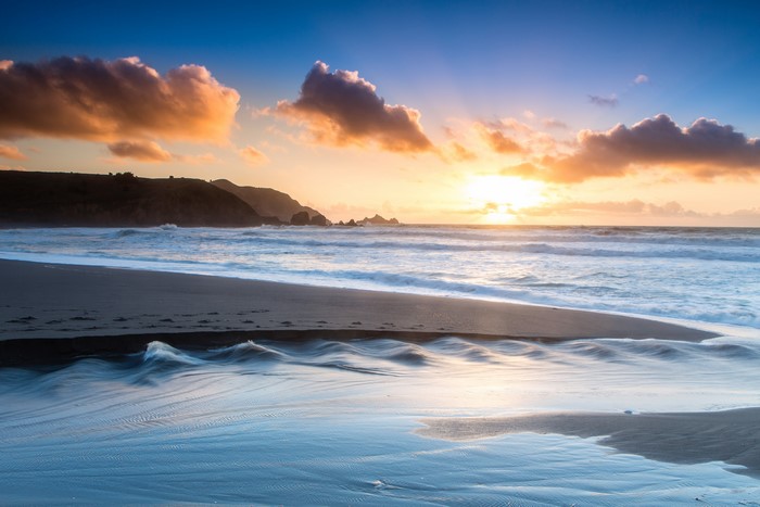 Sunset over the ocean with clouds and beach