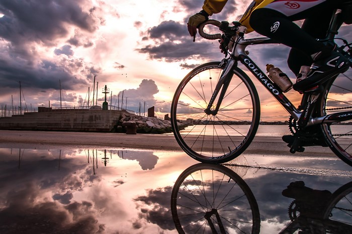 Cyclist on Colnago Bicycle by Water at Sunset