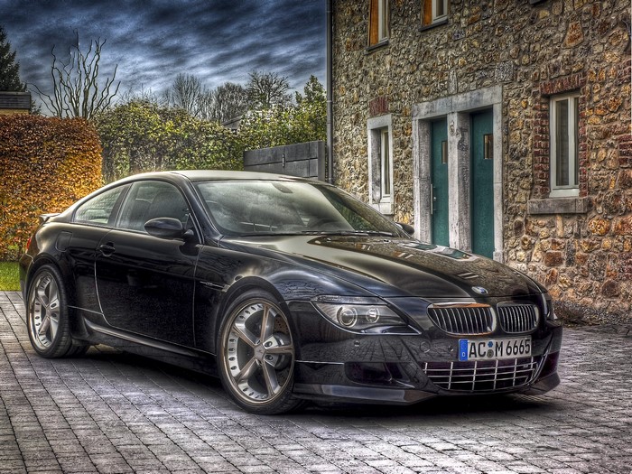 Black BMW M6 parked in front of a stone house