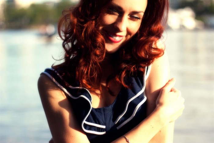 Redhead girl smiling by the water
