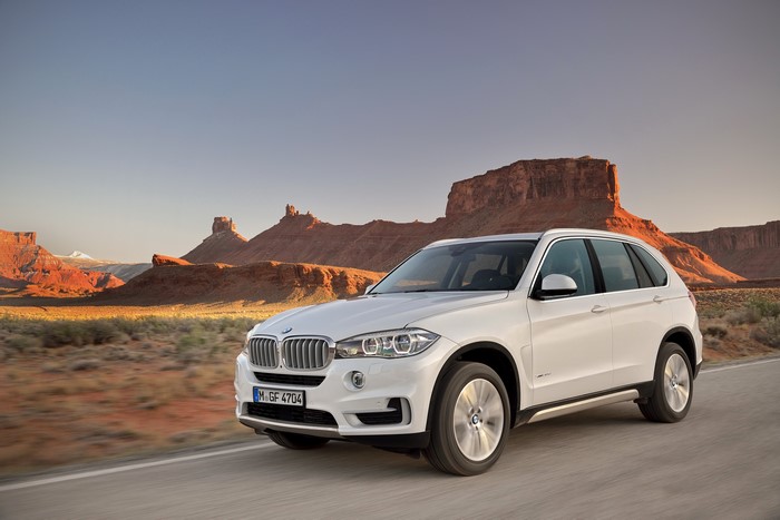 White BMW X5 driving through a desert canyon