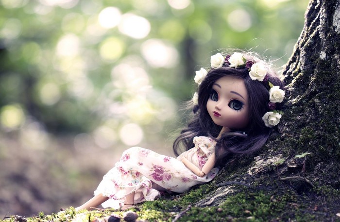 Doll with flower crown sitting by a tree