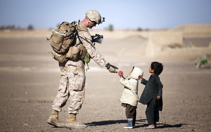 Soldier gives toy to children in desert