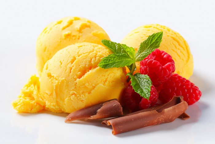 Yellow ice cream scoops with raspberries and mint